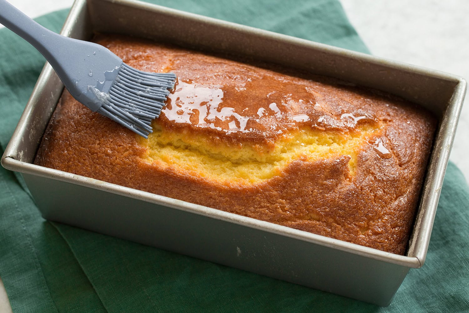 Lemon Pound Cake Baked Lemon pound cake being glazed with lemon simple syrup.