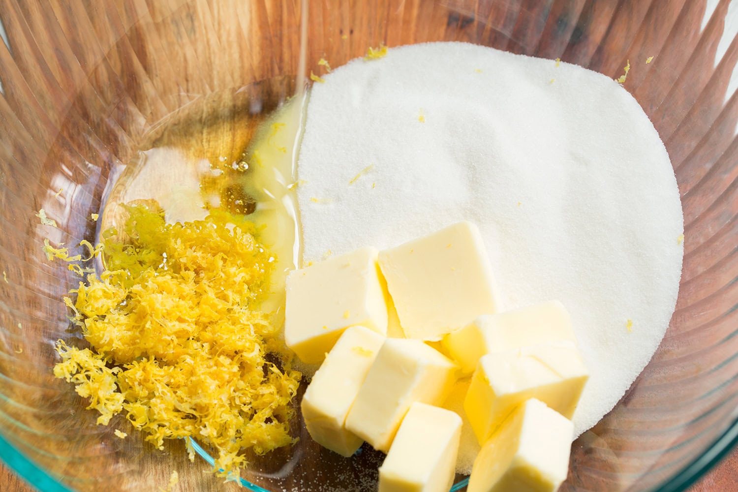 Lemon Pound Cake Softened butter cubes, lemon zest, sugar and oil in a glass mixing bowl.