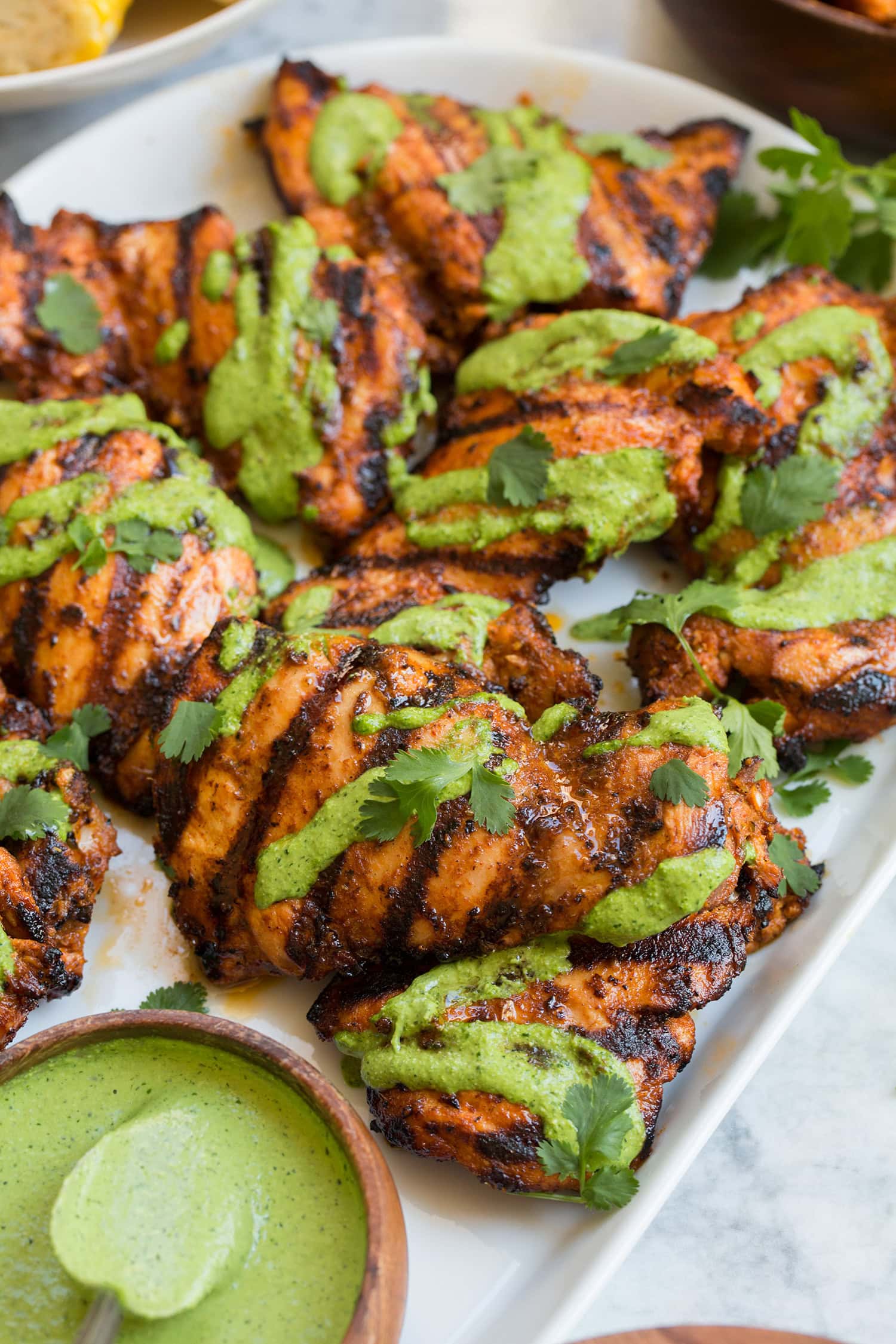 Close up photo of Peruvian style grilled chicken thighs with aji verde sauce drizzled over.