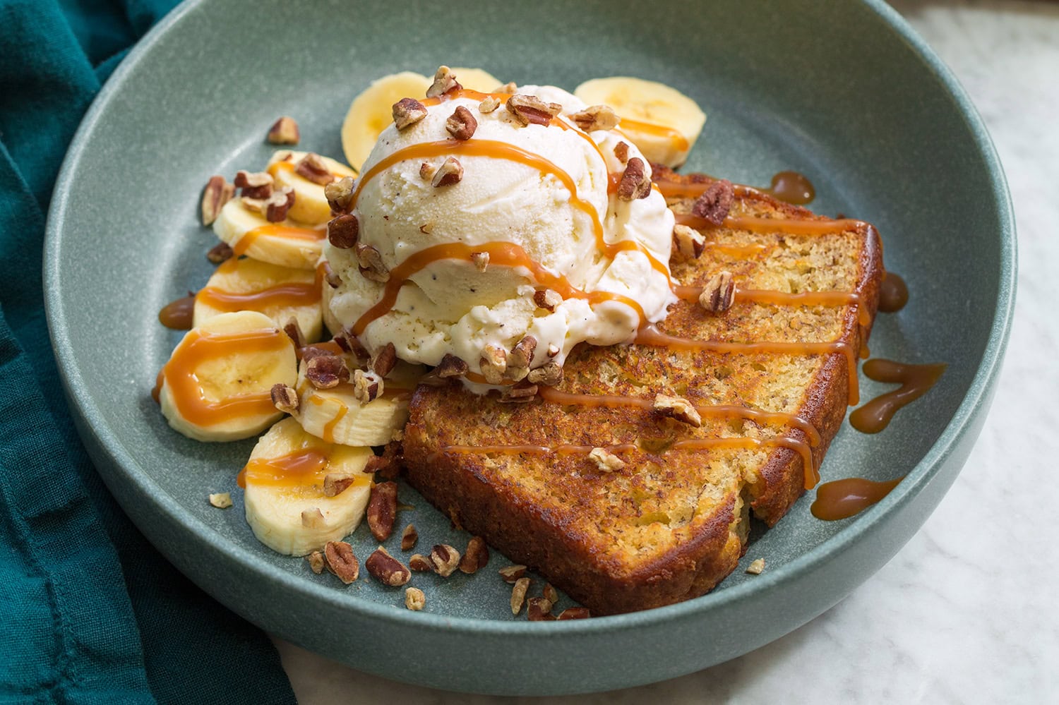 Caramel drizzled over ice cream on banana bread sundae and pecans sprinkled over everything.