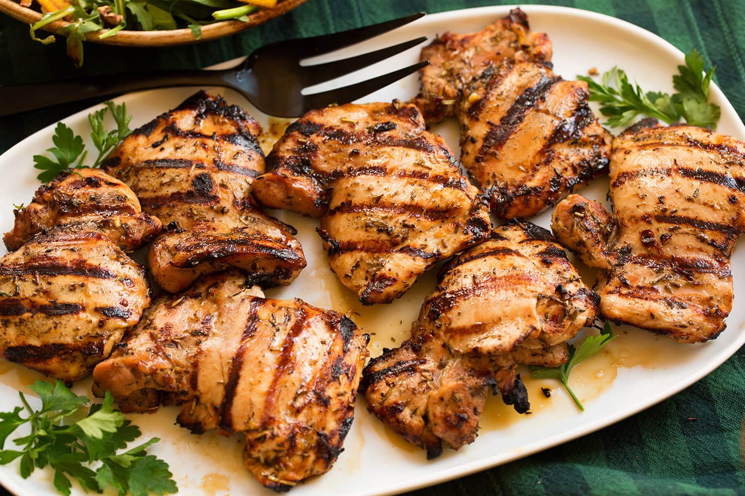 Completed chicken thighs shown on a platter at a side angle.