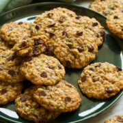 Large green plate with zucchini oatmeal chocolate chip cookies layered on it.